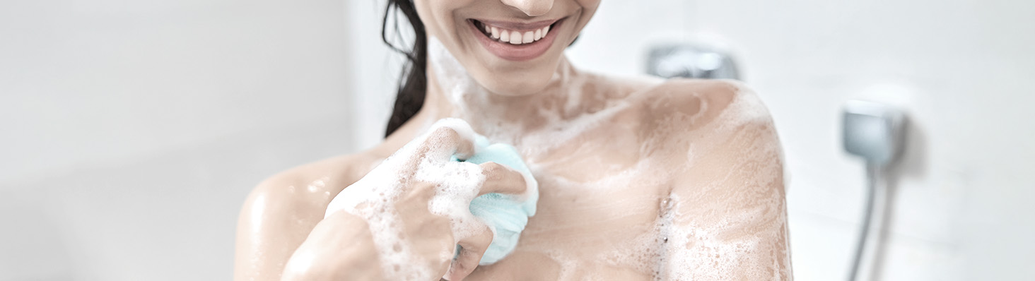 Mujer sonriendo mientras se ducha con jabón Neutro Balance